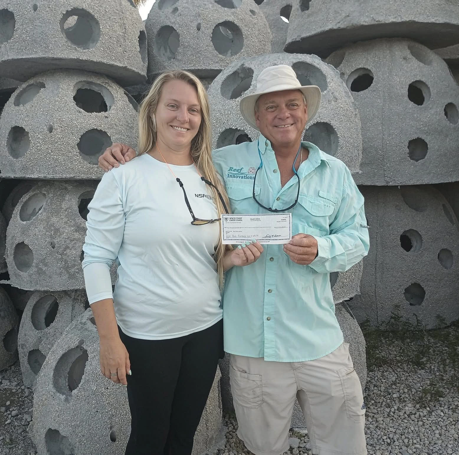 A donation supporting the memorial reef program, presented in front of reef balls awaiting placement.